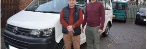 White minibus with two men standing next to it