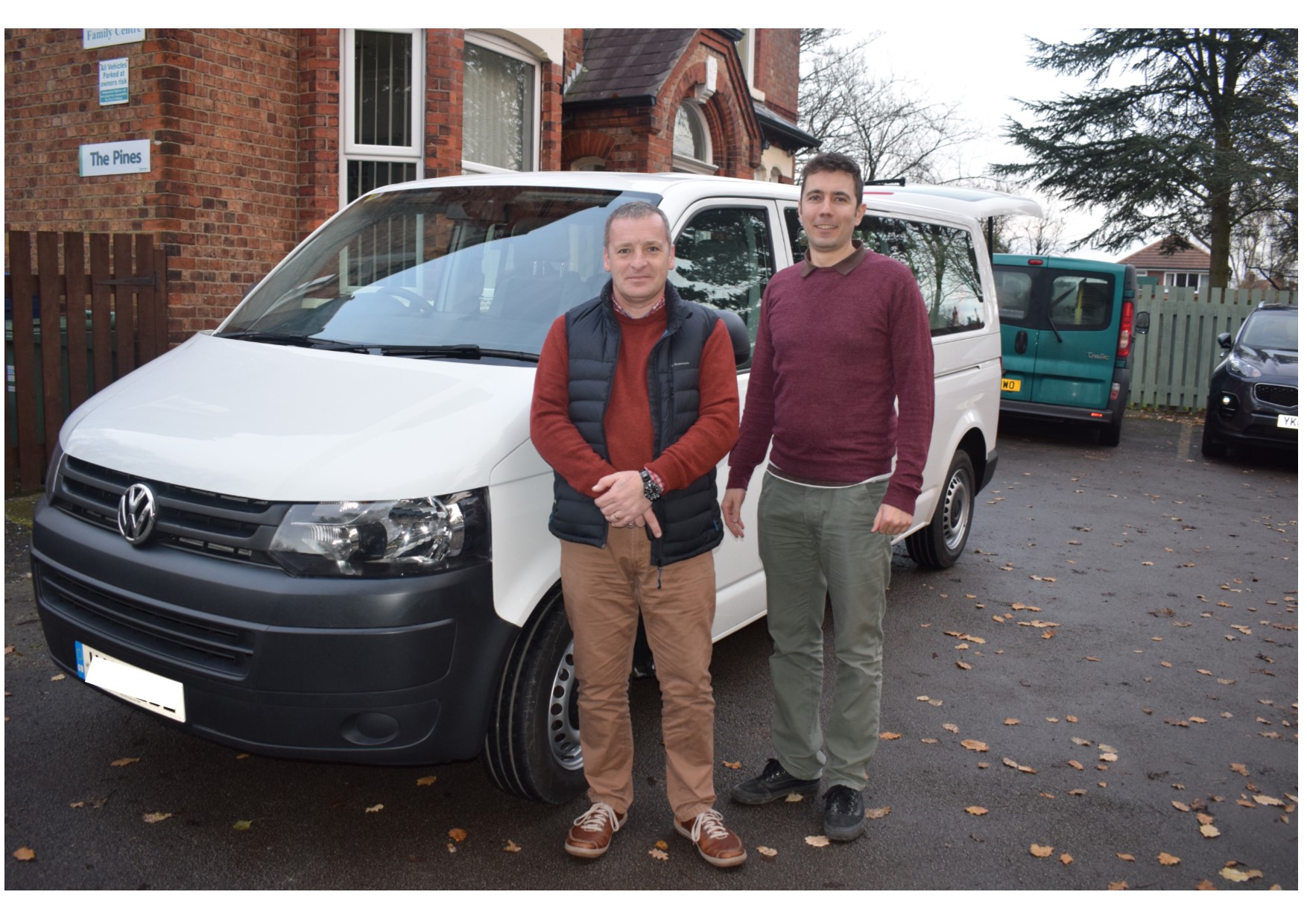 White minibus with two men standing next to it