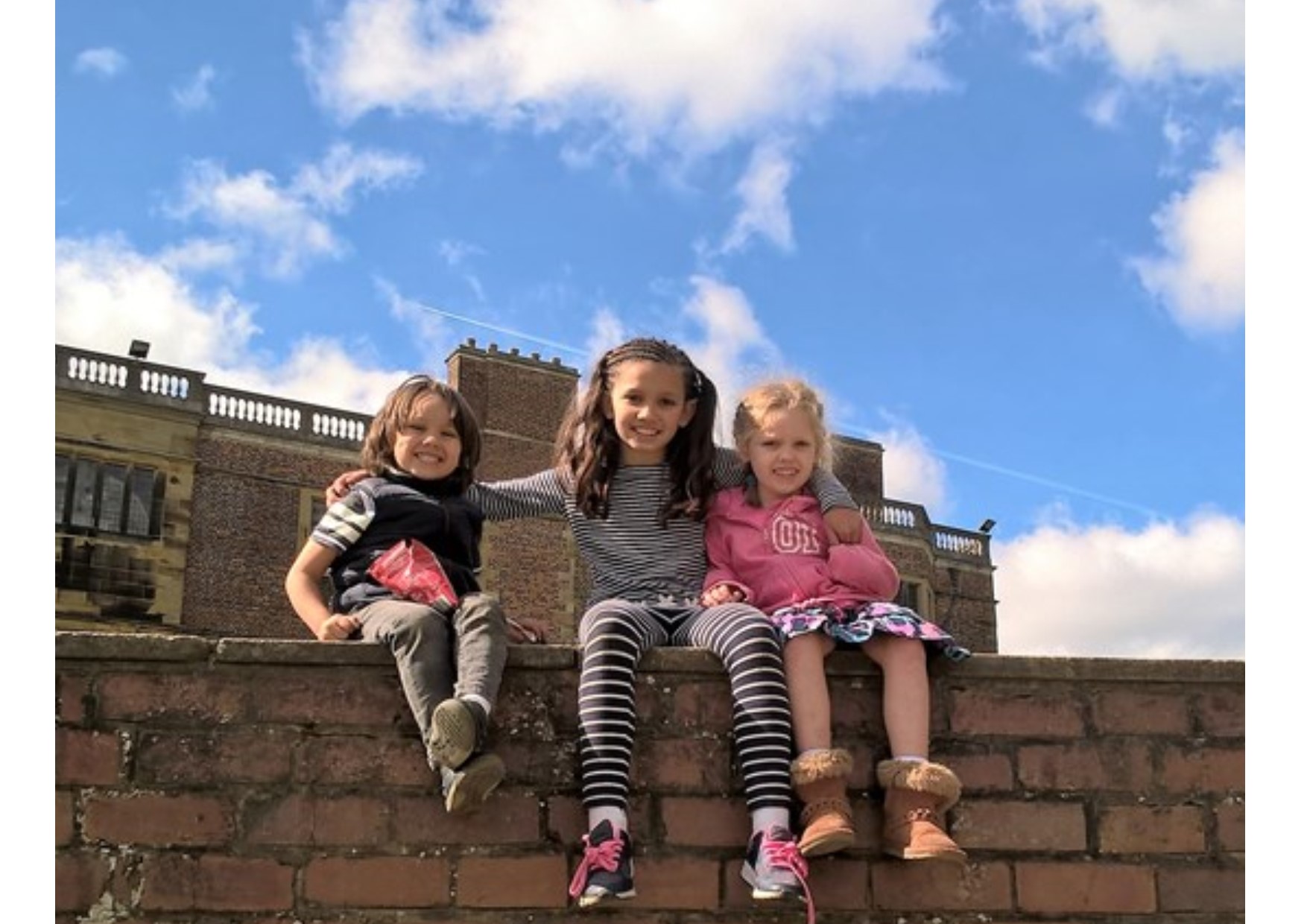 siblings climb on wall in sunshine